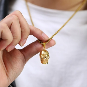 Macro view of gold skull pendant with polished finish and square chain on man