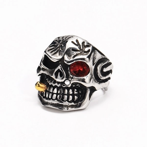 Macro detail of punk skull ring with red rhinestone eye and gold cigar in titanium steel