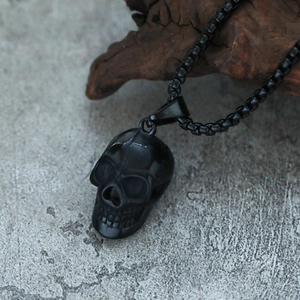 Macro shot of 3D black skull pendant necklace in punk style on natural wood and stone background