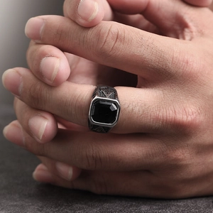 Macro shot of silver Freemason ring featuring a square black stone and engraved symbols
