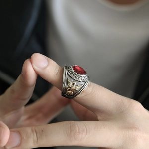 Primer plano del anillo militar retro con gema roja y detalle de águila dorada grabada