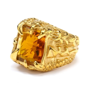 Detailed close-up of eagle claw gold ring with rectangular yellow gemstone and relief carving