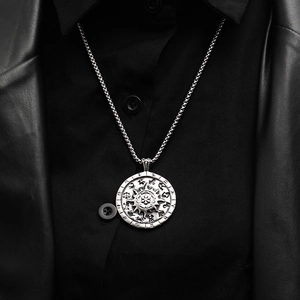 Dettaglio del ciondolo bussola vintage con segni zodiacali su un gilet di pelle nero