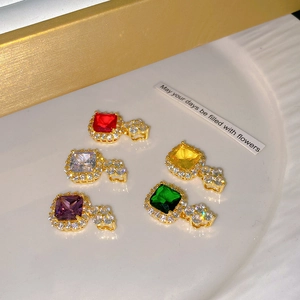 Detailed view of colorful square zircon pendants in halo setting on white textured plate