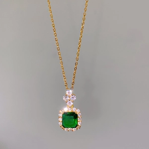 Macro view of gold halo necklace with square green gemstone and white zircon accents
