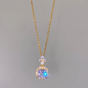 Close-up of golden necklace with square purple zircon and clover pave diamond pendant