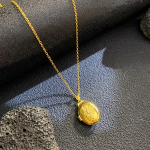 Macro shot of gold oval locket pendant with rhinestone cross flower relief on stone