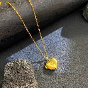 Detail of a golden heart locket necklace with starburst zircon and openable frame