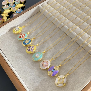 Vintage gold locket necklaces with colorful enamel and zircon patterns on velvet tray