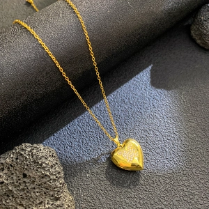 Close-up of golden heart pendant with pavé zircon butterfly detail and cross chain