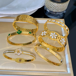 Présentation détaillée de divers bracelets joncs dorés avec motifs trèfles et fleurs