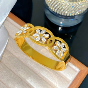Vue détaillée du bracelet doré à trois anneaux ajourés avec fleurs en diamants