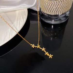 Detail van gouden klaverketting met vijf gebogen bloemenhangers en micro-pave zirkonia's