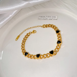 Vue détaillée d'un bracelet gourmette doré en acier inoxydable avec cinq cœurs noirs