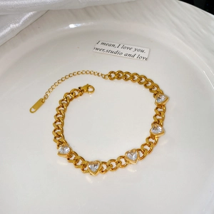 Détail d'un bracelet en acier inoxydable doré avec cinq breloques en zircone en cœur