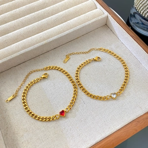Détail de bracelets gourmette dorés avec pierres en zircon de cœur et fermoir homard