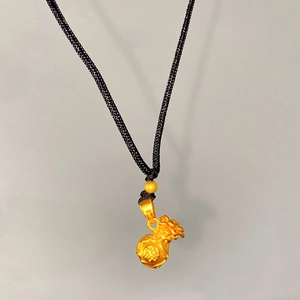 Macro detail of a gold fortune bag pendant with Fu character and black braided cord