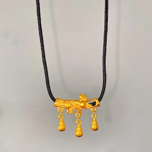 Detailed view of matte gold lotus gourd pendant with intricate branch design and black cord