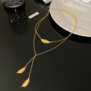 Macro view of gold double-layer necklace featuring sparkling zircon feather pendants