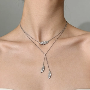 Detail of double-layered silver feather pendant necklace worn on a model's neck