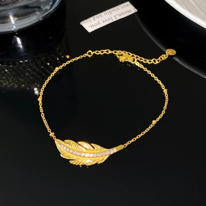 Macro shot of gold feather bracelet with zircon inlay and adjustable lobster clasp