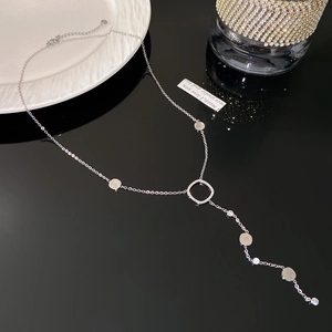 Macro view of a silver Y-shaped rhinestone necklace with polished metal disk details