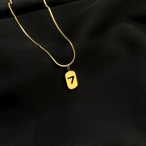 Detailed close-up of golden snake chain and rectangular lucky number 7 pendant on black silk