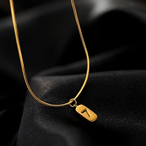 Macro shot of gold snake chain necklace with number 7 rectangular pendant on black silk
