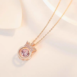 Close-up of rose gold crown pendant featuring a sparkling pink dancing stone on O-chain