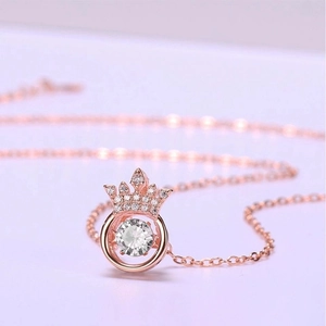 Macro shot of rose gold crown necklace featuring a sparkling suspended center stone