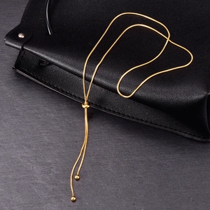 Adjustable golden snake chain necklace with bolo slide clasp on a textured leather bag