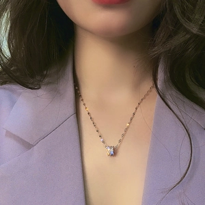Detail of rose gold cylinder pendant necklace with sparkling diamonds on a model