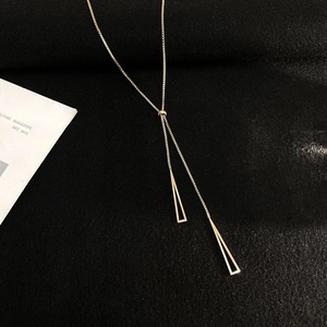 Close-up of rose gold Y-necklace with geometric triangle pendants on black texture