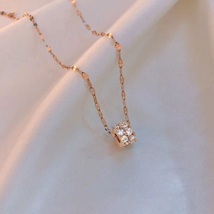 Detail of rose gold cylinder pendant with pavé set crystals on a textured chain