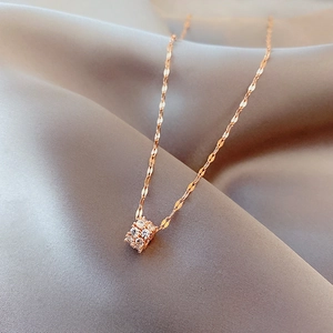 Macro shot of rose gold necklace pendant with pavé crystals on draped satin fabric