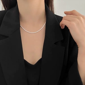 Primer plano de un collar de cadena de plata minimalista y brillante en el cuello de una modelo