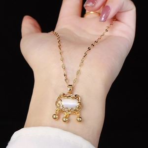Dettaglio del ciondolo Longevity Lock dorato con pietra occhio di gatto bianca e perline