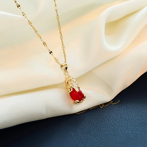 Close-up of gold-plated pendant necklace featuring a red gemstone and pave zircon details