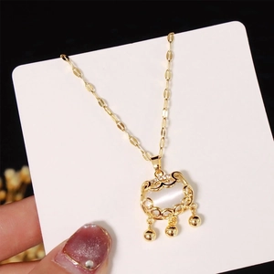Dettaglio della collana con lucchetto d'oro, pietra occhio di gatto e tre campanelli