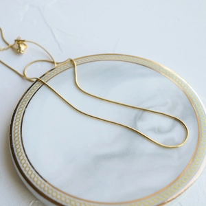Minimalist gold snake chain necklace for women displayed on an elegant marble tray