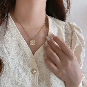Elegant gold four-leaf clover necklace with cat eye stone and zircon on woman's neck