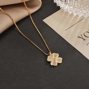 Close-up of golden clover necklace featuring yellow cat-eye stone petals and zircon