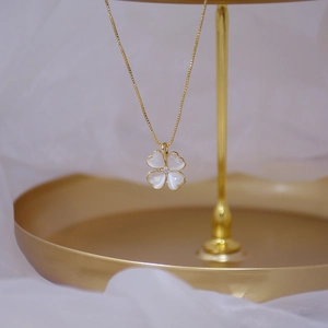 Macro detail of gold clover pendant with cat-eye stone petals and center crystal
