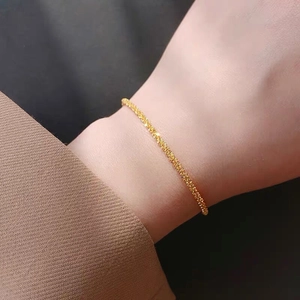 Close-up of minimalist gold twist chain bracelet with a sparkling starry texture on a wrist
