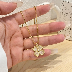 Golden clover pendant necklace with white cat eye stones and central crystal inlay