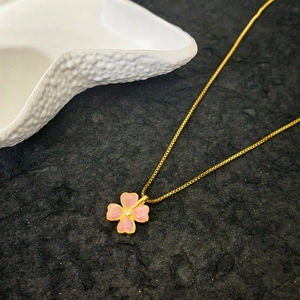 Pink cat eye four leaf clover necklace with gold chain on dark textured stone