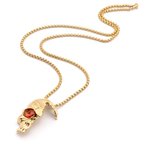 Detail der goldenen Totenkopf-Halskette mit rotem Edelsteinauge und runder Boxkette auf Weiß