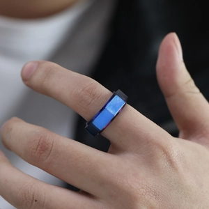 Makroaufnahme eines facettierten blauen Edelstahlrings mit gebürsteter Textur auf der Haut