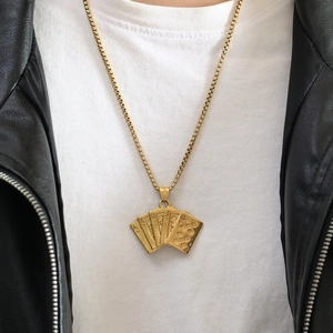 Detail of golden royal flush poker pendant with box chain on a male model's neck