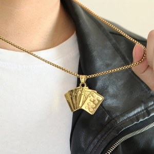 Detail of gold poker flush pendant necklace on black leather jacket and white shirt